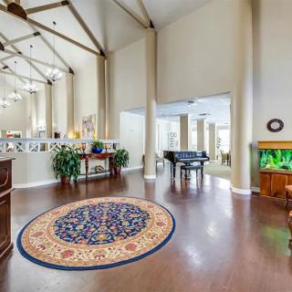 A spacious living room featuring a grand piano, hardwood floors, and a vibrant fish tank.