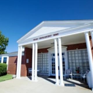 An exterior view of a building with white columns and a brick facade under a clear blue sky.