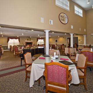 A spacious dining area with neatly arranged tables and chairs, featuring a carpeted floor and large windows.