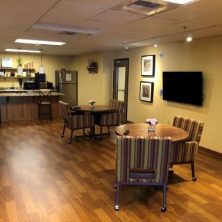 A modern indoor room with a kitchen area, tables, and chairs.