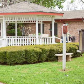 A cozy backyard with a gazebo surrounded by neatly trimmed bushes and a well-maintained lawn.