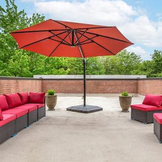 A spacious patio with red cushioned seating and a large red umbrella.