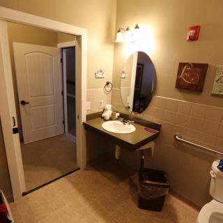 A well-lit bathroom featuring a sink, mirror, and tasteful wall art.