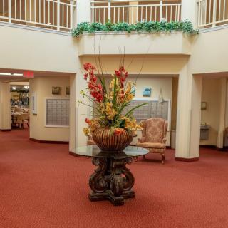 A well-decorated lobby with a central floral arrangement and seating area.