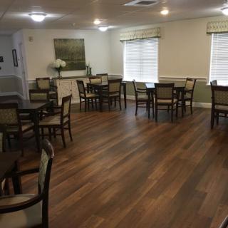 A dining area with wooden flooring and neatly arranged tables and chairs.