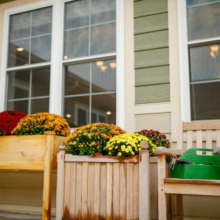 Colorful mums in wooden planters decorate the exterior of a house.