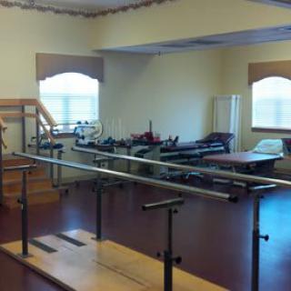 A rehabilitation room featuring parallel bars and other physical therapy equipment.