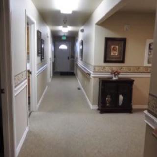 A well-lit hallway with framed pictures and a small cabinet.