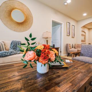 A cozy living room featuring a beautiful floral arrangement on a wooden table, complemented by modern decor elements.