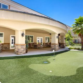 A beautifully designed outdoor patio area with a mini golf lawn under a clear blue sky.