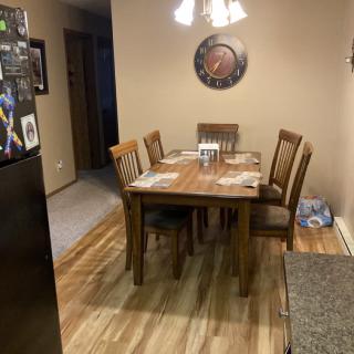 A cozy dining room with a wooden table and four chairs, illuminated by overhead lighting.