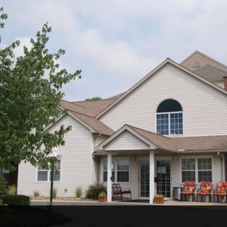 A suburban residential house with a porch and surrounding greenery.