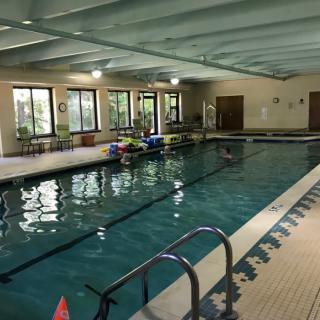 An indoor swimming pool with a view of windows and surrounding amenities.