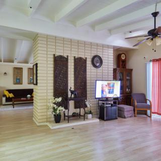 A modern living room with wooden flooring, decorated with minimalist furniture and a television mounted on a brick accent wall.
