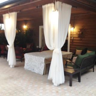 A cozy outdoor patio with curtains and seating area.
