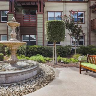 A peaceful courtyard with a fountain and bench surrounded by greenery.