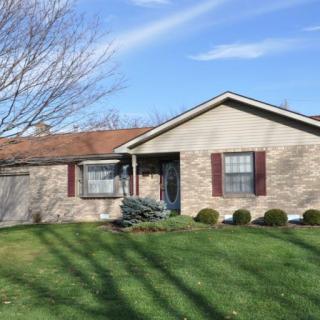 A suburban brick house with a well-maintained lawn and clear blue sky.