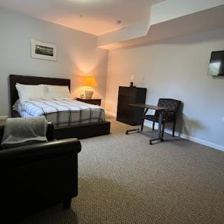 A cozy and well-furnished bedroom featuring a bed, desk, and warm lighting.