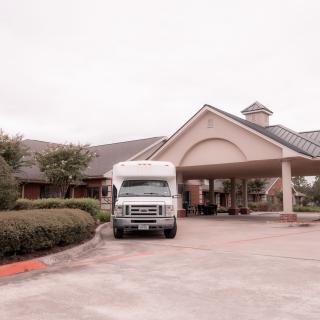 A van parked in the driveway of a building's entrance.