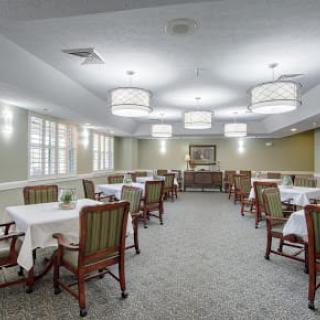 A spacious dining room with neatly arranged tables and chairs, accented by elegant lighting.