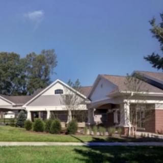 A suburban residential house with a well-maintained lawn and surrounding trees.