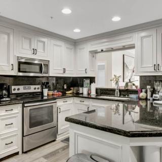 A modern kitchen featuring stainless steel appliances and white cabinets with granite countertops.
