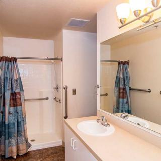 A clean and well-lit bathroom with a shower curtain and large mirror.
