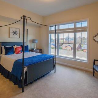 A modern bedroom with a four-poster bed, large windows, and stylish decor.