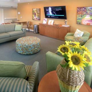 A cozy living room with green sofas, a central coffee table, and sunflowers as decor.