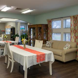 A cozy dining and living area featuring a table set for meals and a comfortable couch, adorned with subtle decor.