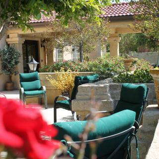 A serene patio setting with green cushioned chairs and lush garden surroundings.