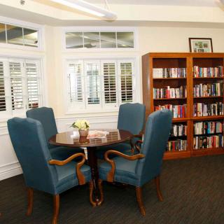 A cozy library reading area with a table and chairs surrounded by bookshelves.