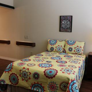 A cozy bedroom with a colorful patterned bedspread.