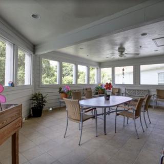 A sunroom with a dining table, surrounded by windows and filled with natural light.