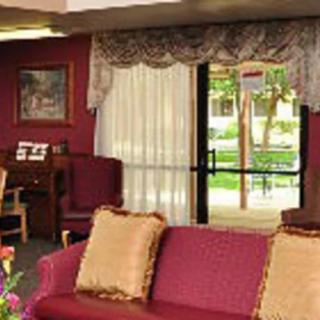 A cozy living room with a red couch, piano, and elegant curtains.