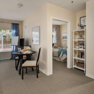 A cozy apartment interior showcasing a dining area adjacent to a living space, with a view into the bedroom.