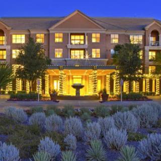 A beautifully lit hotel exterior surrounded by landscaped gardens at dusk.