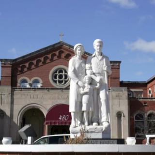 A statue of a family in front of a historic building.