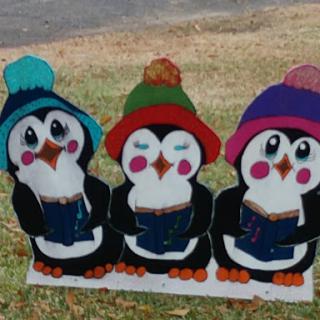 Three adorable penguins wearing colorful hats, enjoying a cozy reading session.