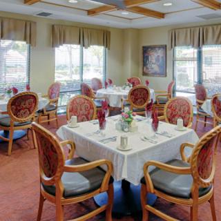 An elegantly decorated dining room with neatly arranged tables and chairs, featuring large windows that provide ample natural light.