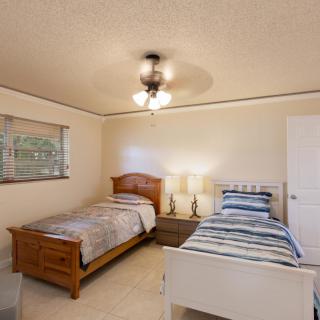 A cozy bedroom with twin beds, a ceiling fan, and a lamp between the beds.