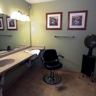 A makeup room with a vanity, chair, and framed artwork on the walls.
