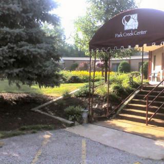 An inviting entrance to a building with an awning and surrounding greenery.