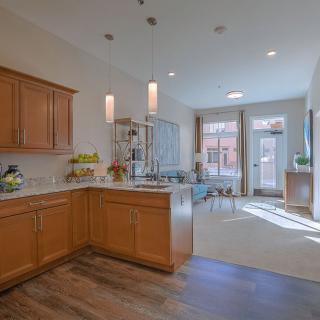 A modern kitchen with wooden cabinets and an open dining area filled with natural light.