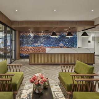 A modern lobby with green seating and a mosaic wall behind the reception desk.