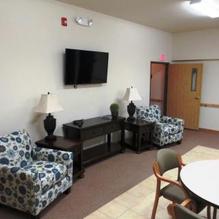 A waiting room with patterned chairs, a television, and lamps.