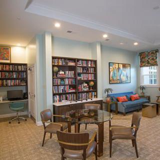 A cozy library room with bookshelves, a seating area, and a computer desk.