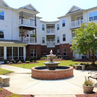 A modern apartment complex with a central courtyard featuring a decorative fountain and well-maintained landscaping.