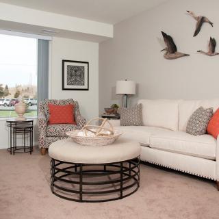 A modern living room featuring a neutral color scheme with a white sofa, artistic wall decor, and a round coffee table.