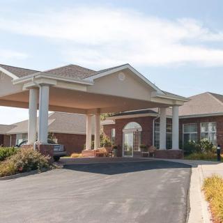A large building with a driveway and covered entrance featuring columns.
